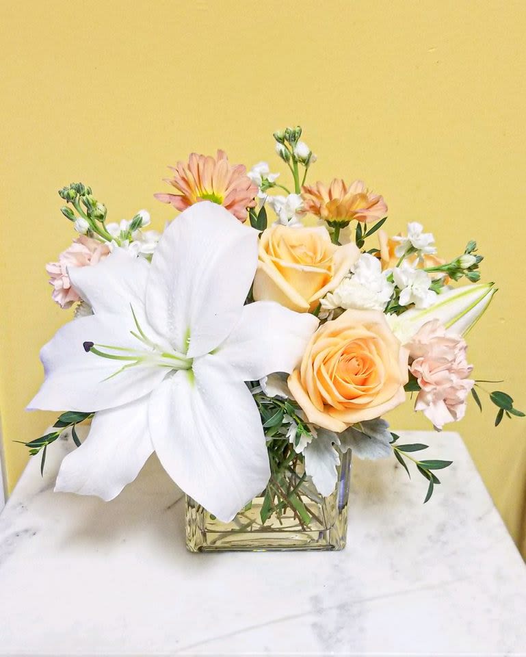 Bouquet of white lilies and peach roses in a glass vase