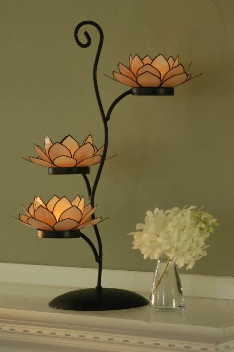 Three orange lotus-shaped candle holders on a black metal stand
