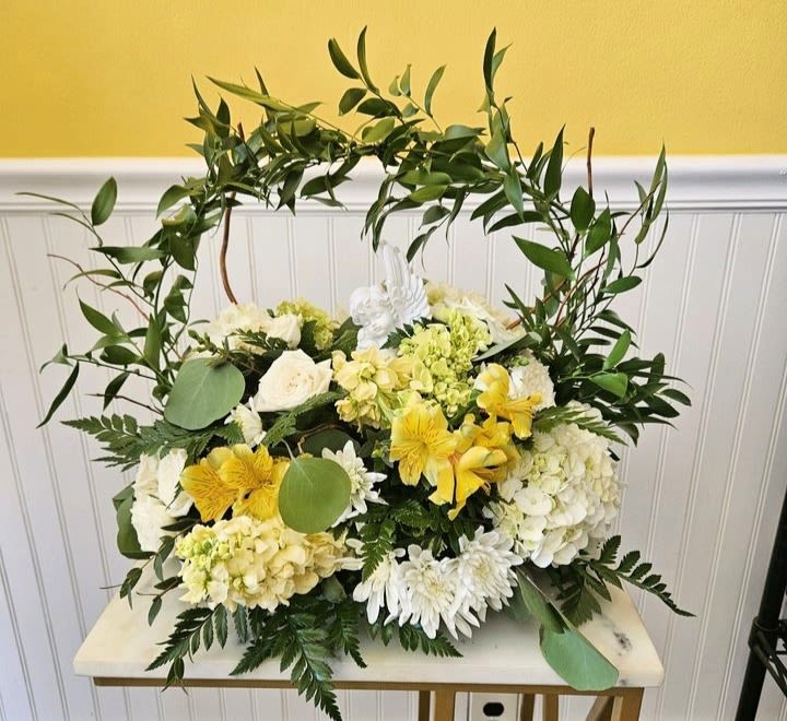 White and yellow floral arrangement with a leafy arch