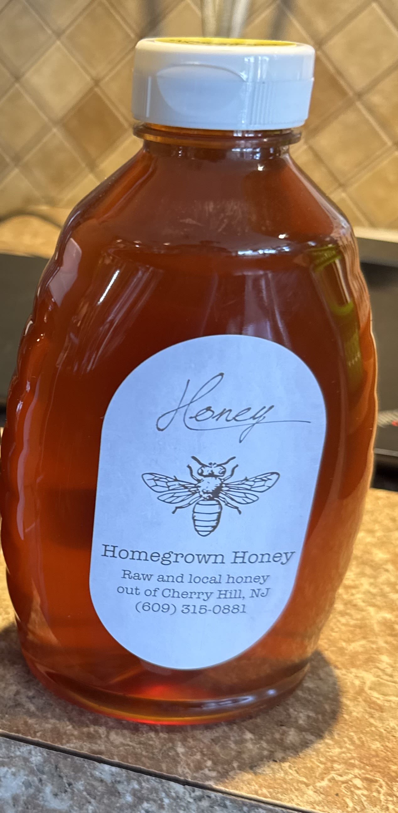 Bottle of honey with a white cap and labeled front
