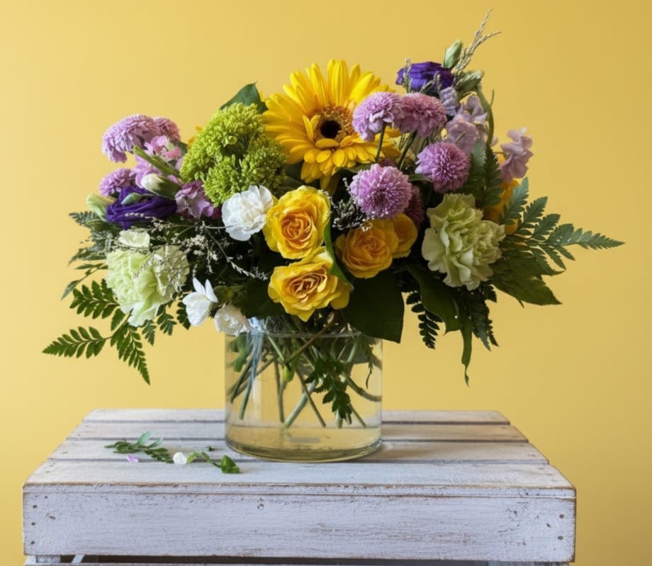 Jubilee  - Sending a jubilation of flowers is a joyful way to brighten any celebration. This yellow, purple and green arrangement is eye-catching, colorful and captivating.   approx.  dimensions 14 in X 14 in