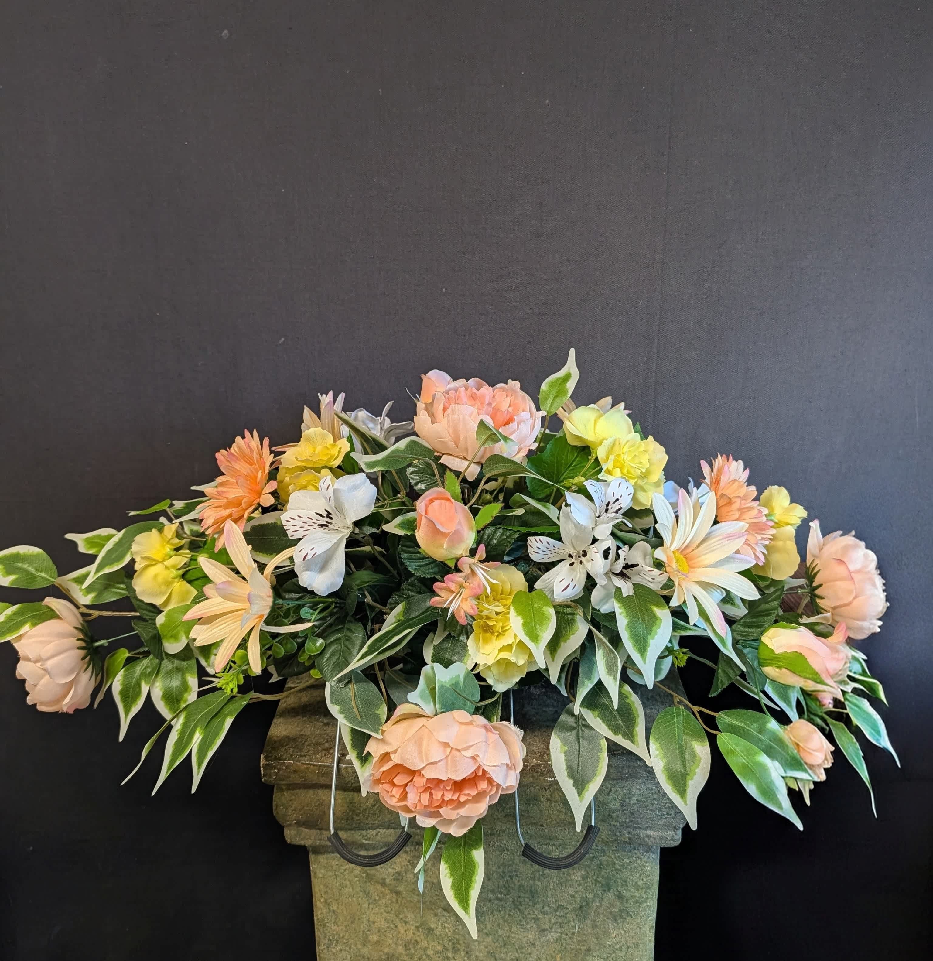 Peach and yellow floral arrangement in a stone urn