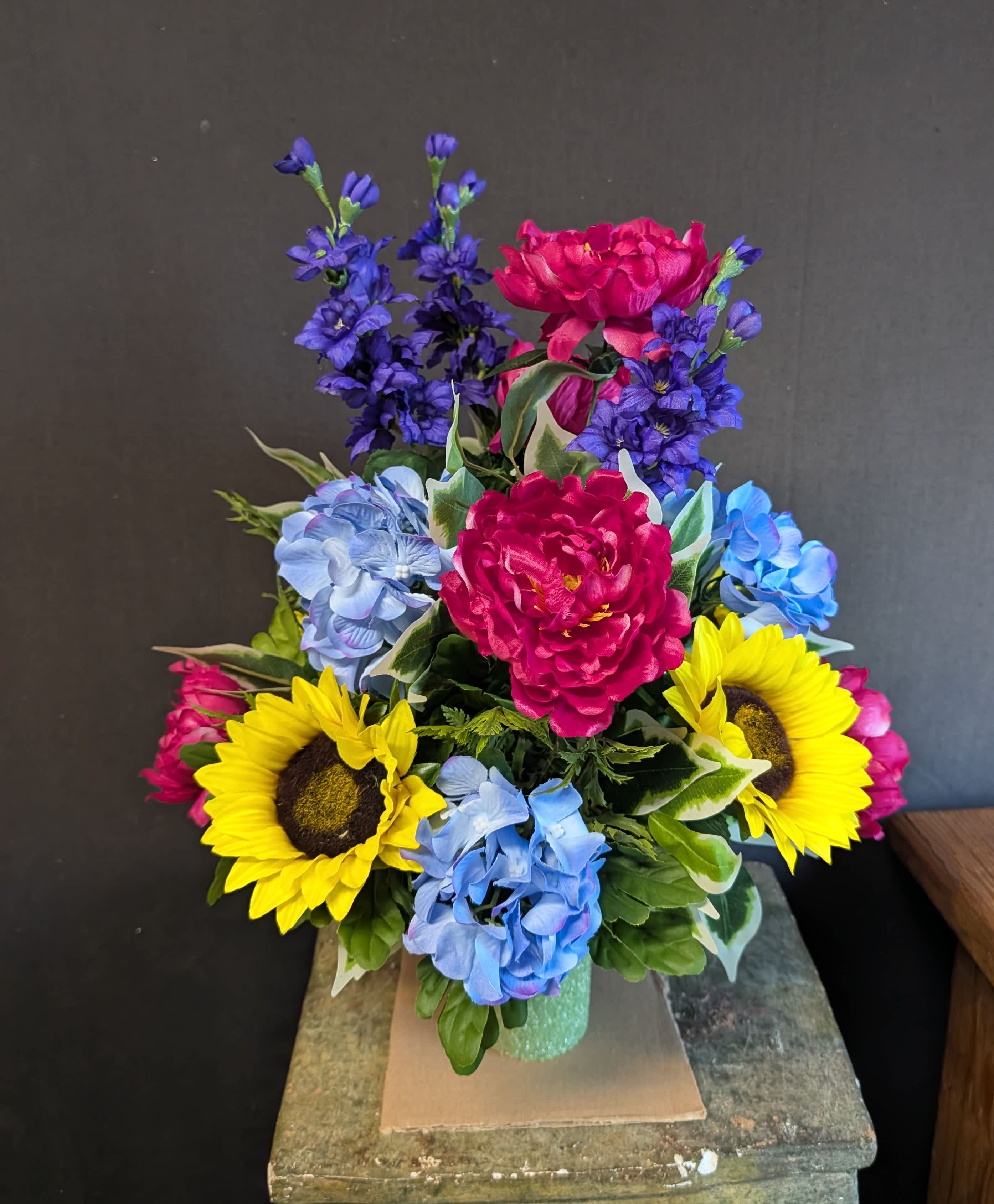 Colorful bouquet with sunflowers, blue hydrangeas, and pink peonies in a vase