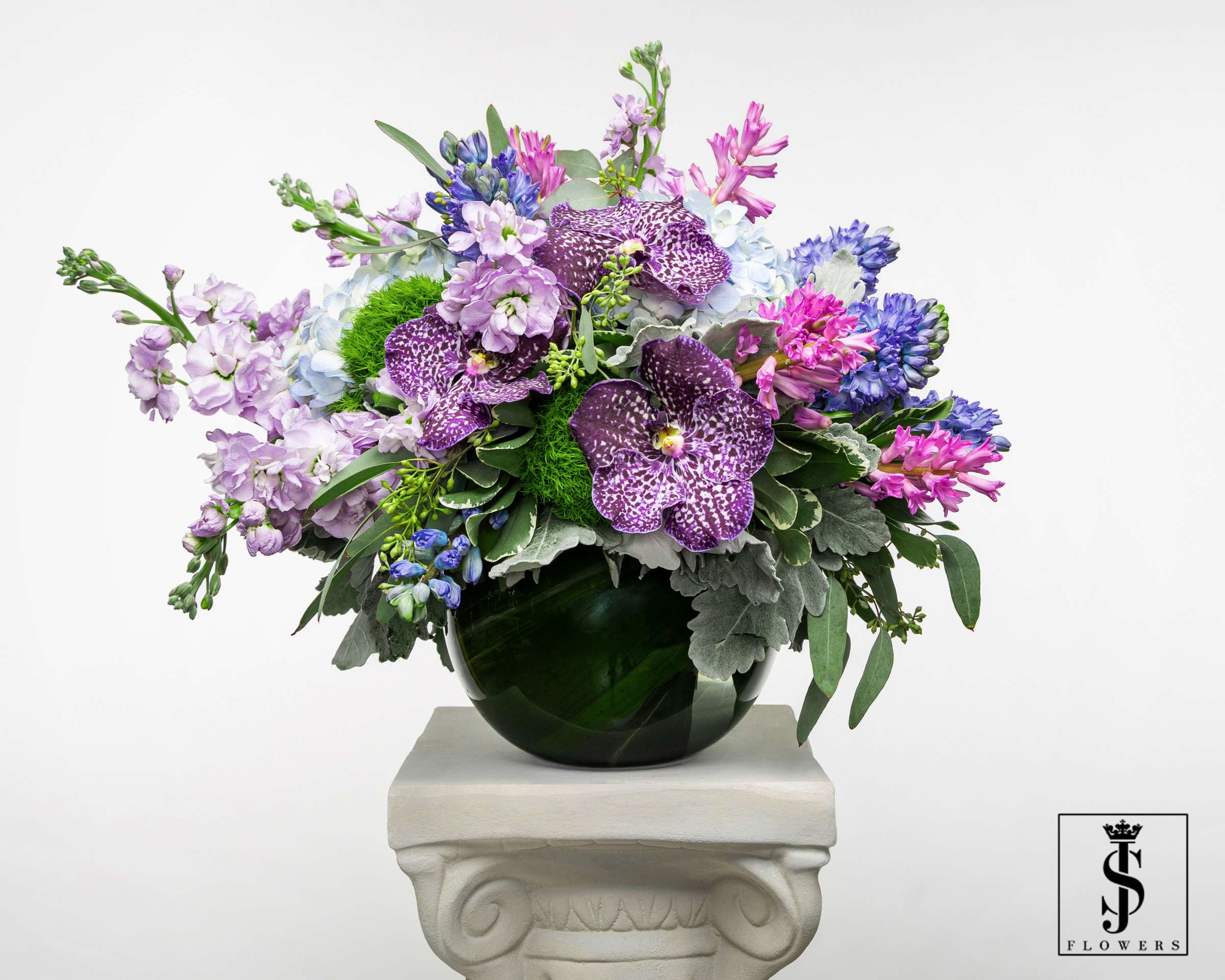 Mixed purple and blue flowers arranged in a dark glass vase