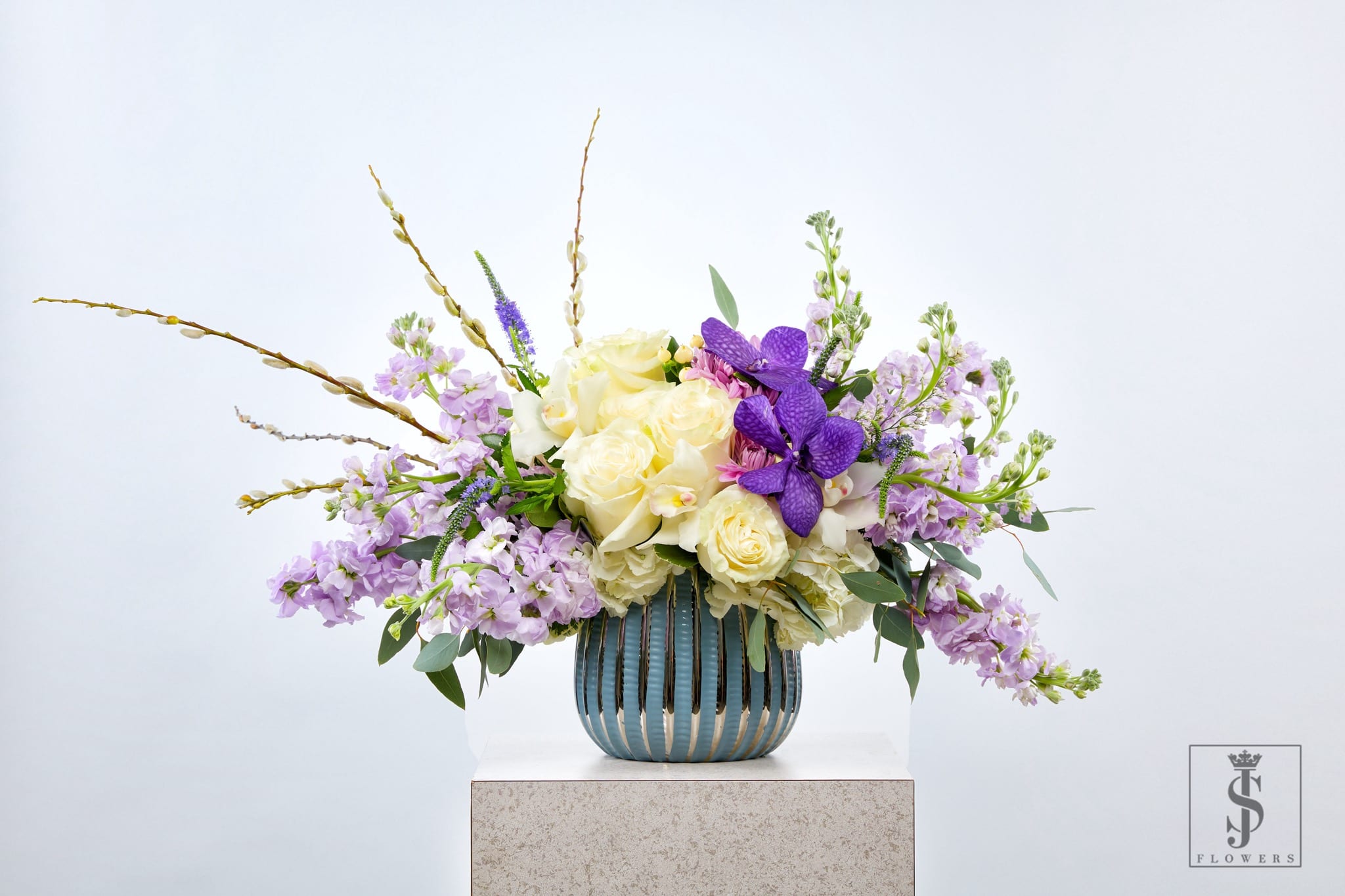 Lavender and cream floral arrangement in a blue striped vase