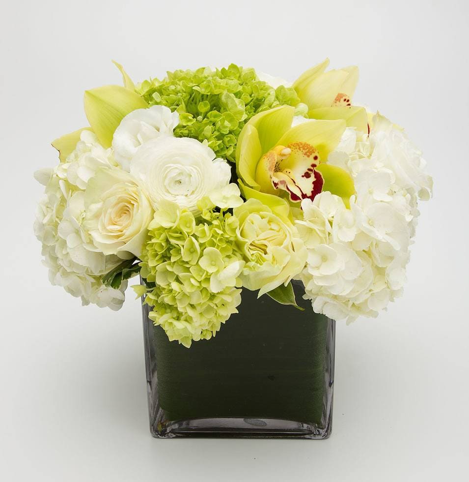 White and pale yellow flowers arranged in a square glass vase