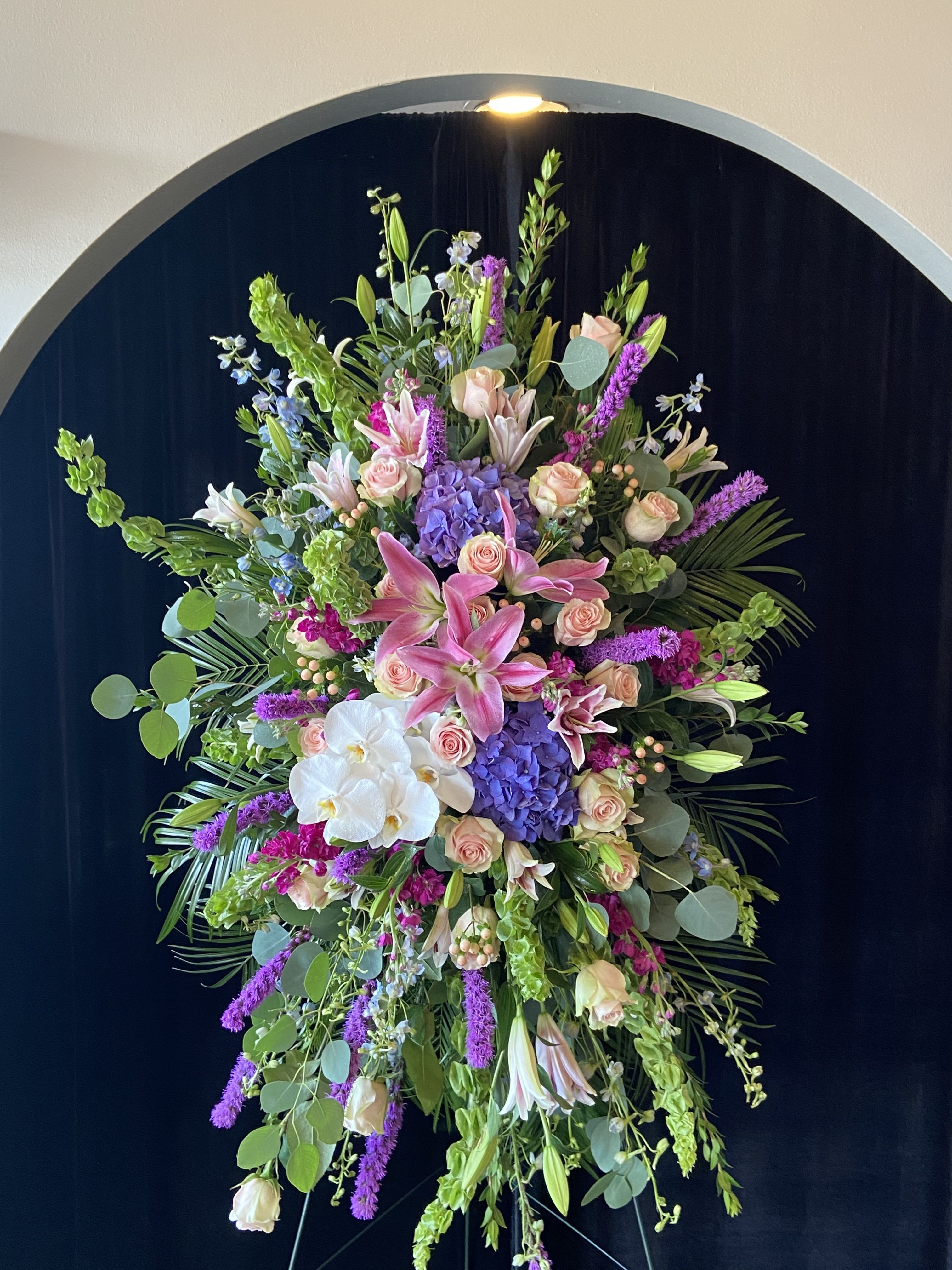 Large standing floral spray with pink lilies, roses, orchids, and purple blooms