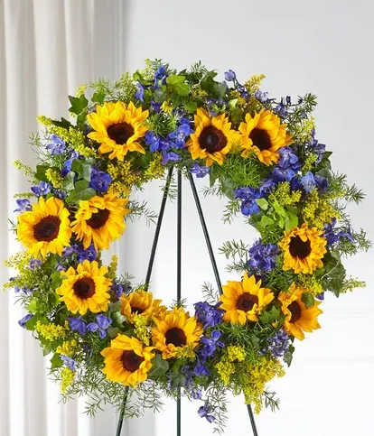 Sunflower wreath with blue flowers on a black stand