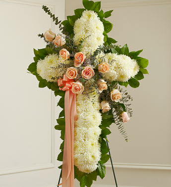 Peach Peace and Prayers Cross (Easel Stand) - This beautiful floral tribute shows your compassion, faith and love during this difficult time. This standing spray arrangement â in the shape of a cross â is created from fresh peach roses, white football mums, spiral eucalyptus and more. Traditionally sent directly to the funeral home by family members or friends and displayed on a stand. Our florists use only the freshest flowers available so varieties and colors may vary. Measures approximately 36"H x 26"L without easel.