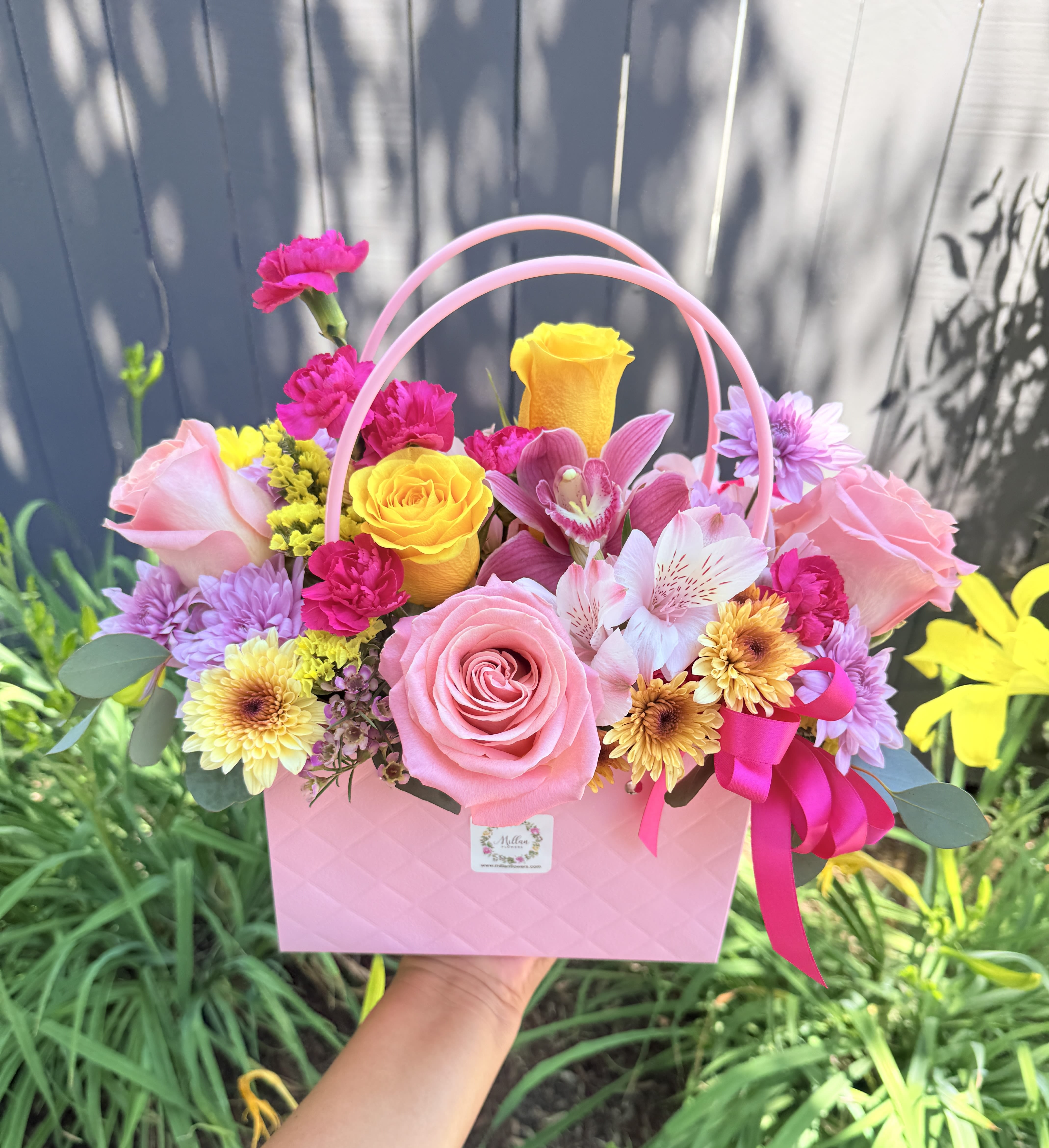 “ Joyful Moments “ Gorgeous Floral Bag  - Beautiful floral bag crafted with beautiful Ecuadorian roses, alstroemerias, fancy daisies,  mini carnations,  seasonal foliage and filler flowers. It’s accented with a beautiful orchid  Medium size  Spring happy tones Note: some flowers might vary depending on the season and availability. Recipient always receives beautiful blooms. 