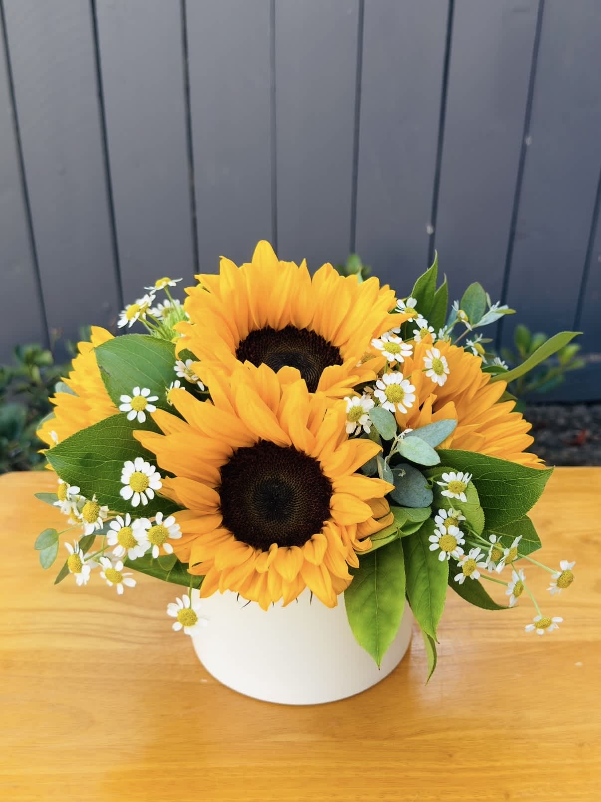Sunflower bouquet in a white vase with small white daisies