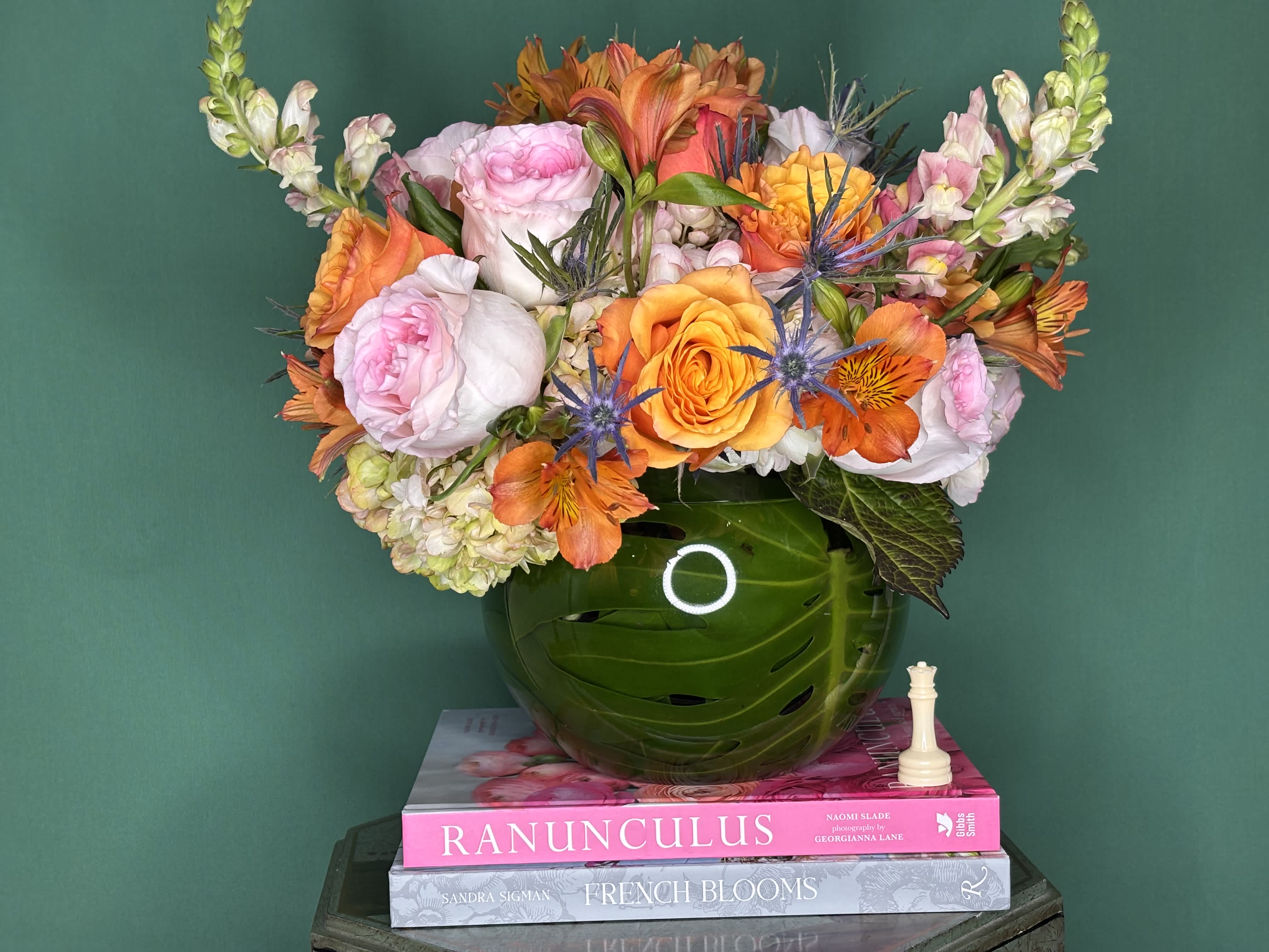 Mixed bouquet of pink, orange, and white flowers in a green vase