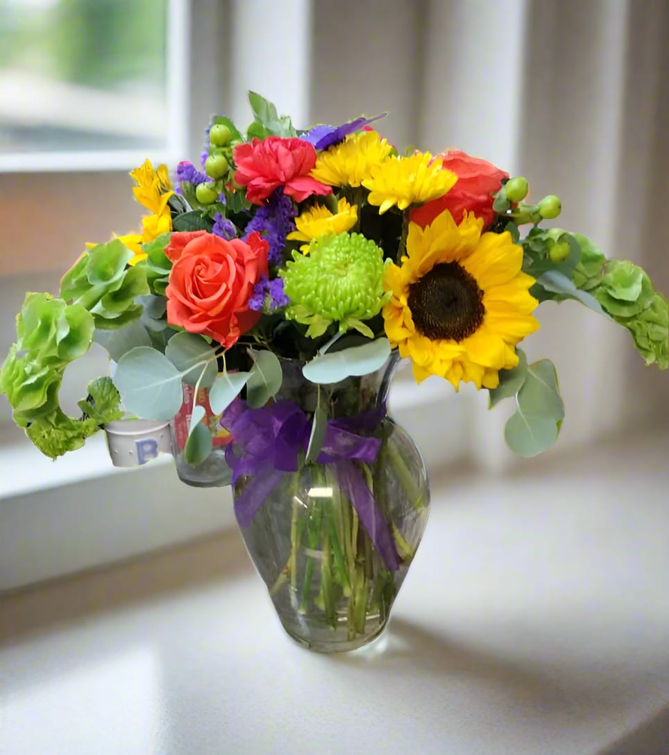 Colorful bouquet with sunflowers, roses, and chrysanthemums in a glass vase