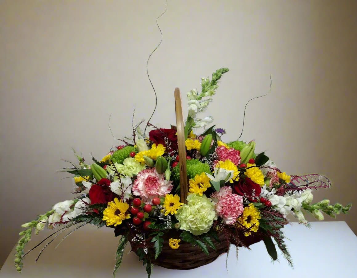 Basket arrangement of mixed red, yellow, white, and green flowers