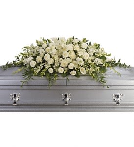 White floral casket spray on a gray coffin
