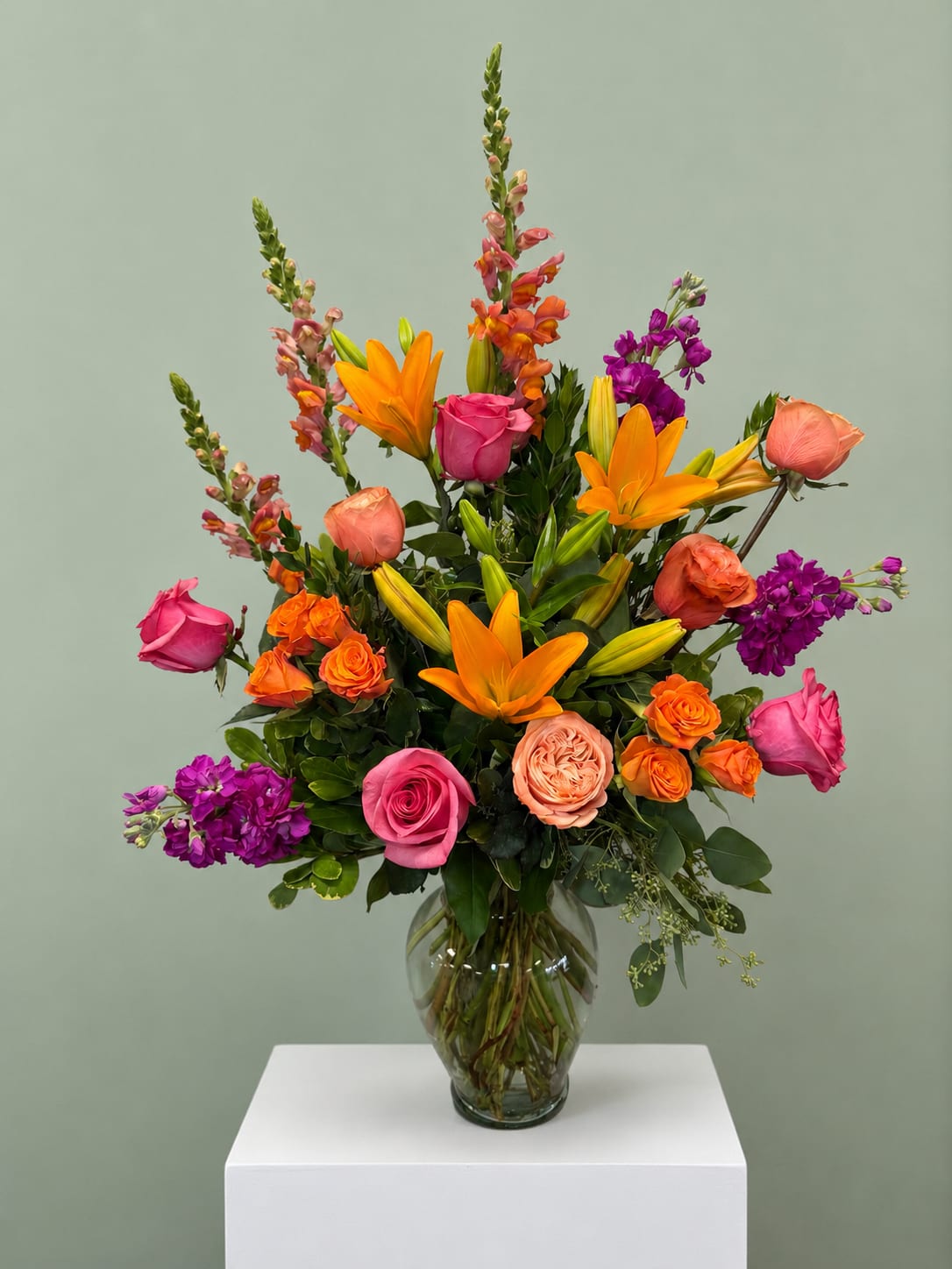 Colorful mixed bouquet in a clear glass vase with roses and lilies