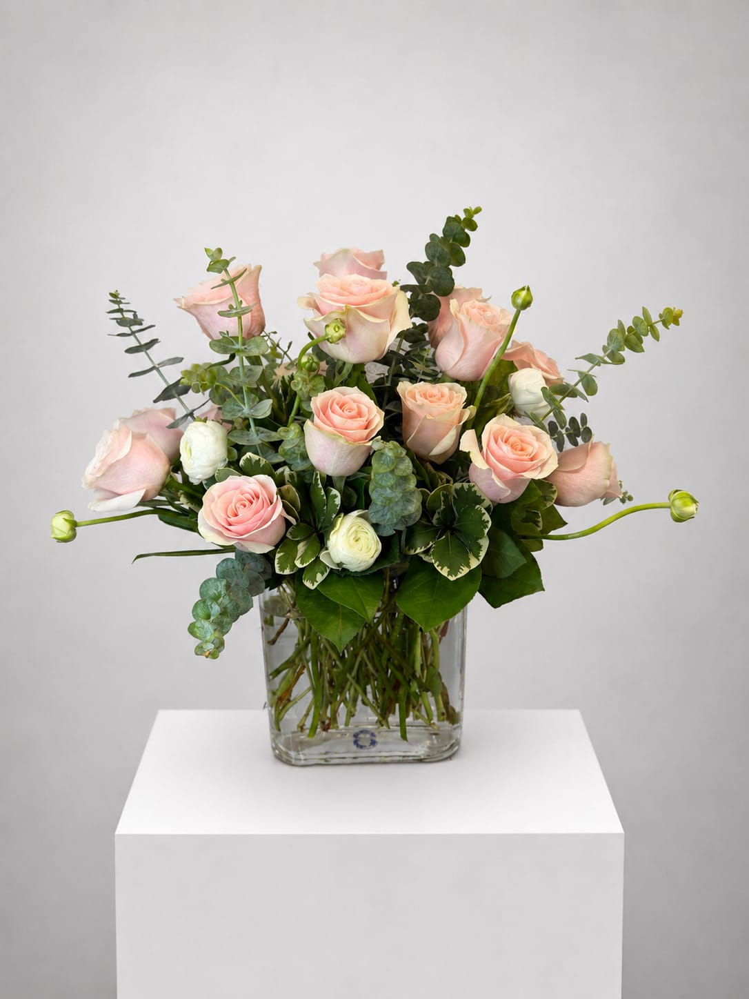 Pink roses and white blooms in a clear glass vase