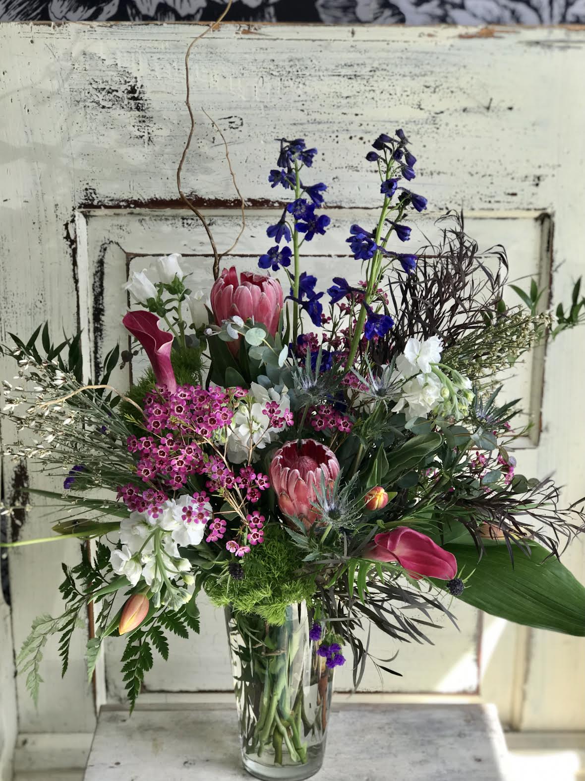 Mixed bouquet in a clear glass vase with pink, white, and blue flowers