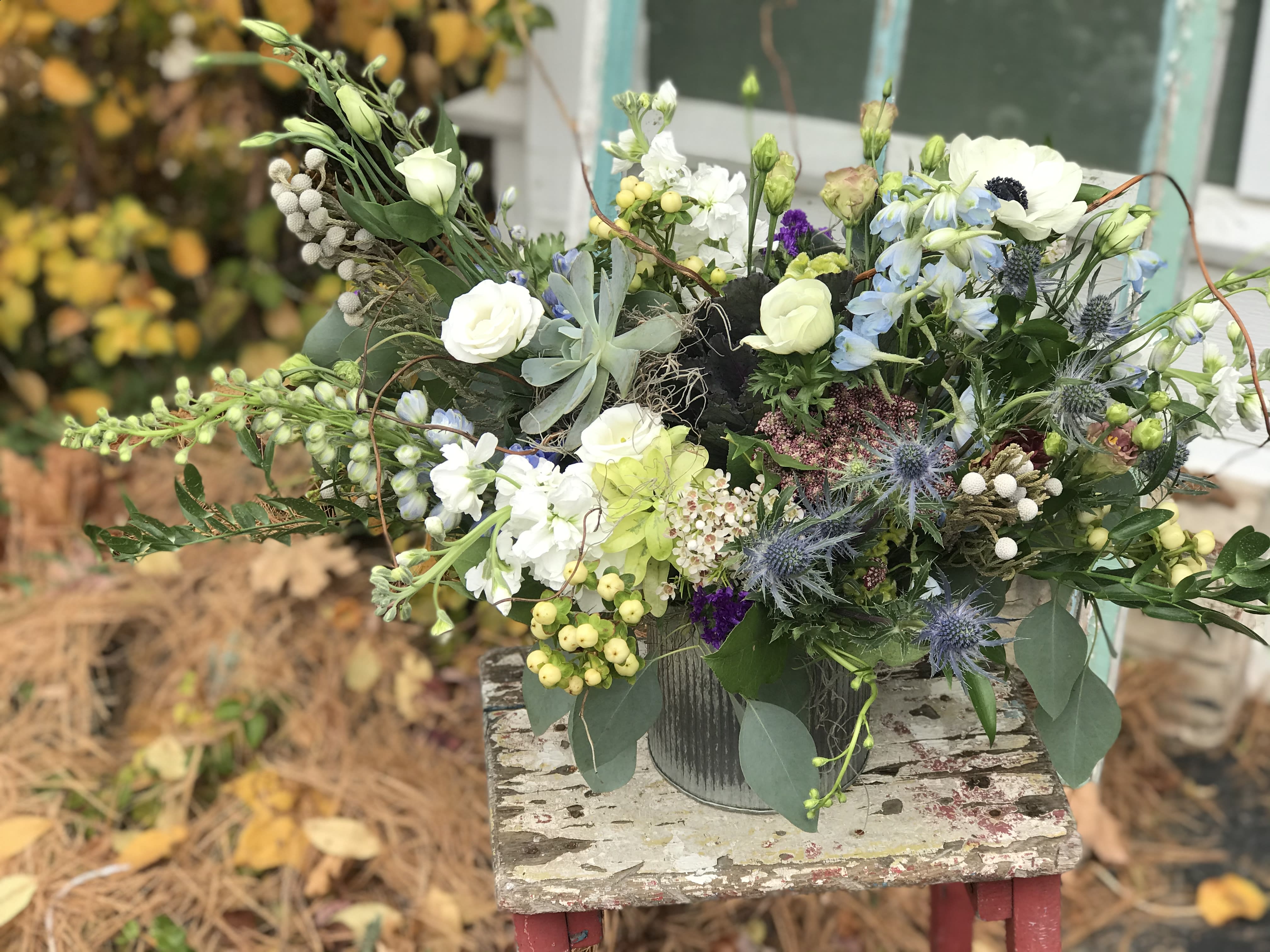 Mixed bouquet in a metal container with white, blue, and green flowers
