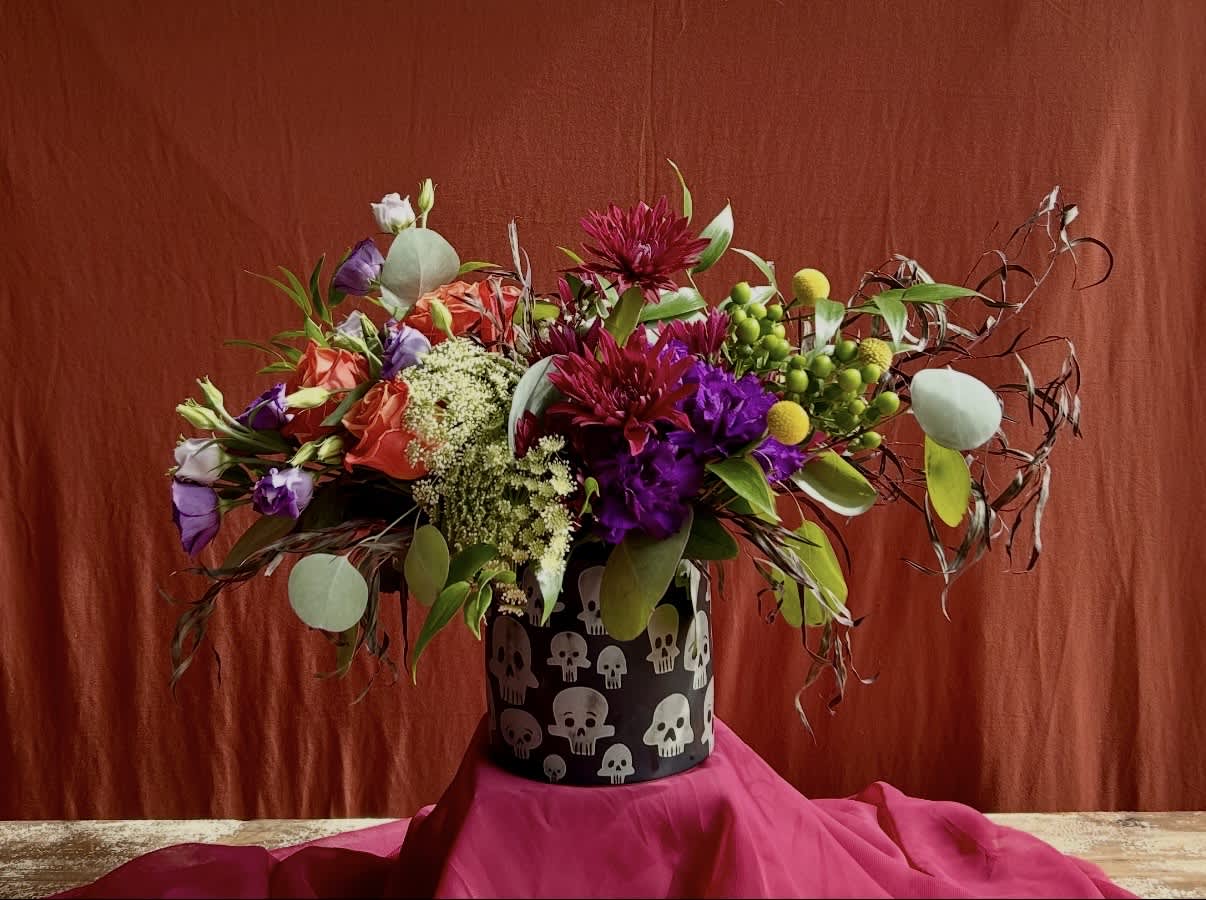 Colorful mixed bouquet in a black skull-patterned container