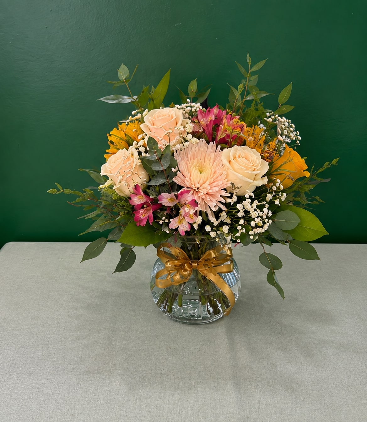 Mixed bouquet of roses, daisies, and pink flowers in a glass vase