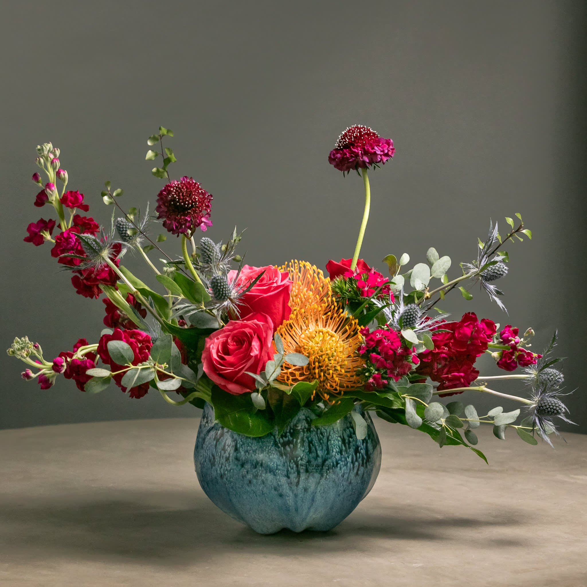 Mixed bouquet of red and pink flowers in a blue vase