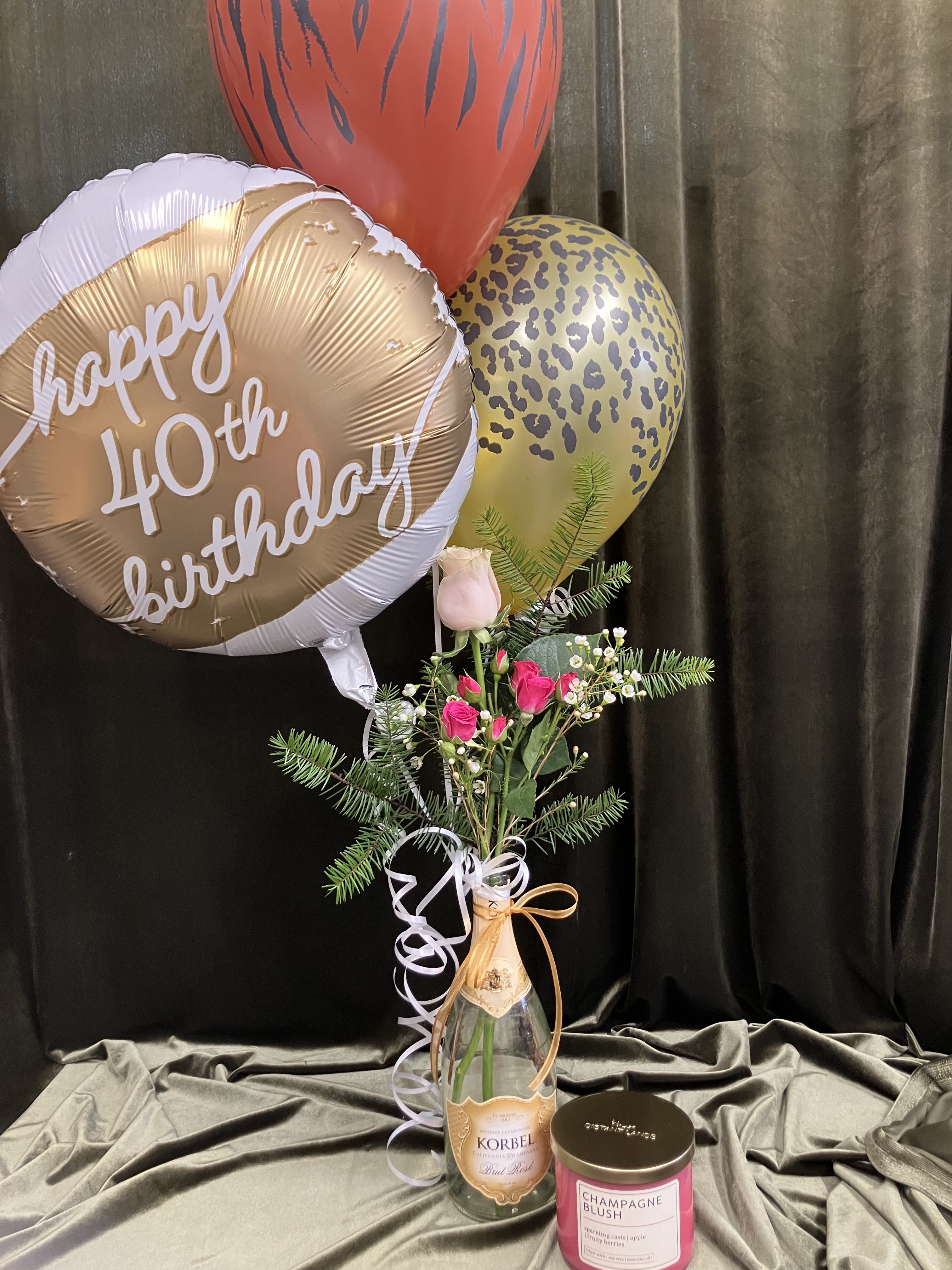 Birthday balloons with a small pink rose arrangement in a bottle vase