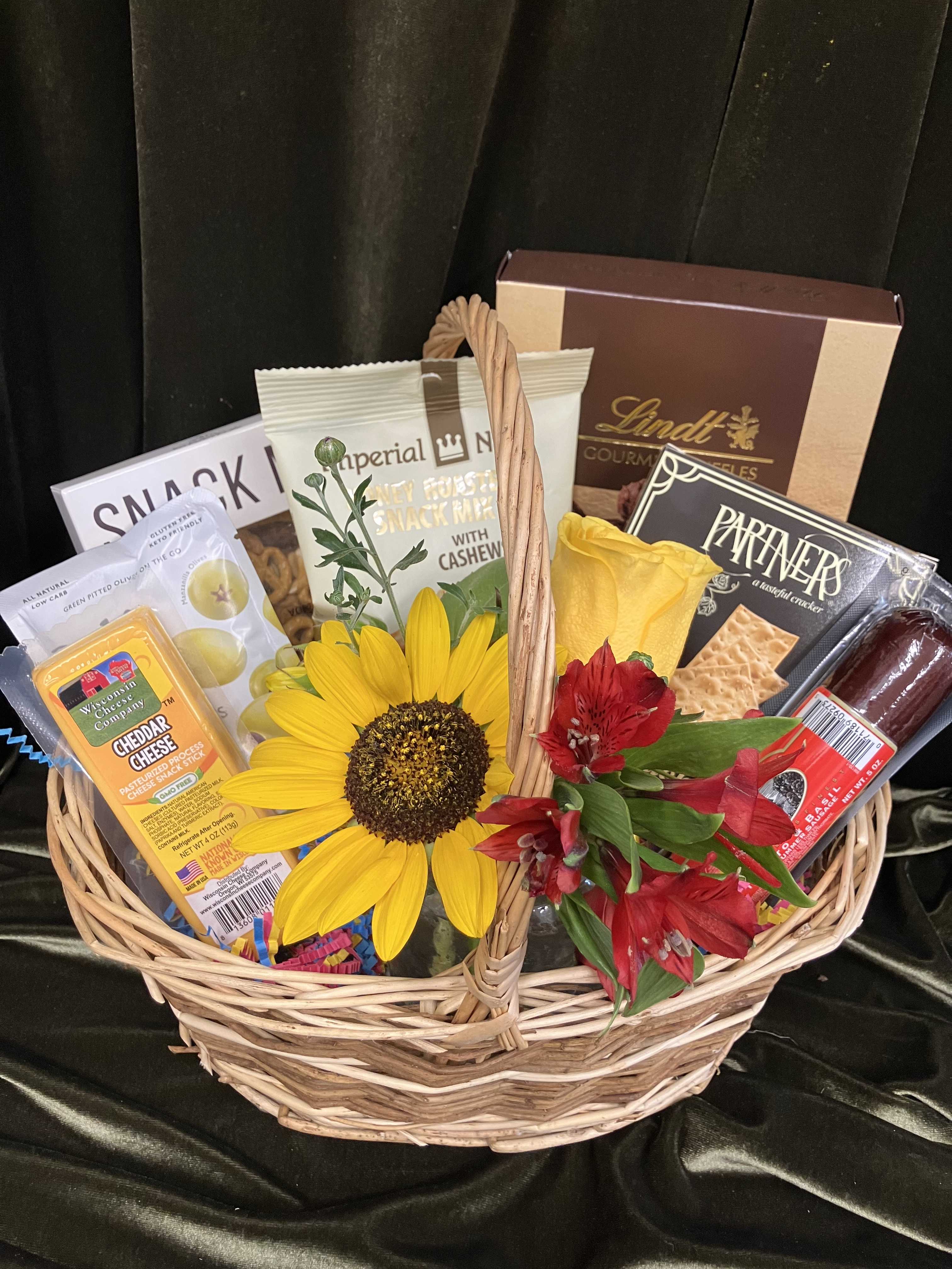 Gift basket with snacks, chocolates, and yellow and red flowers