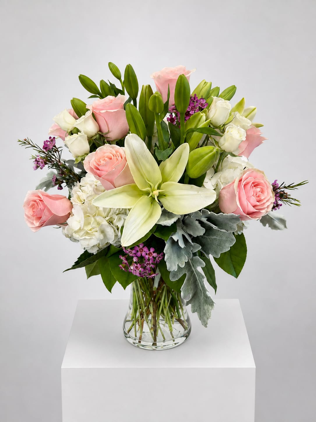 Pink roses and white lilies arranged in a clear glass vase