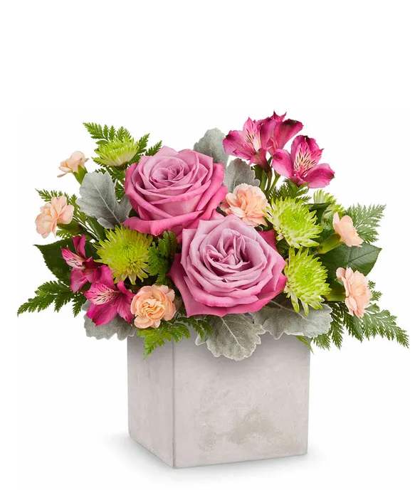 Pink roses and mixed blooms in a square gray vase