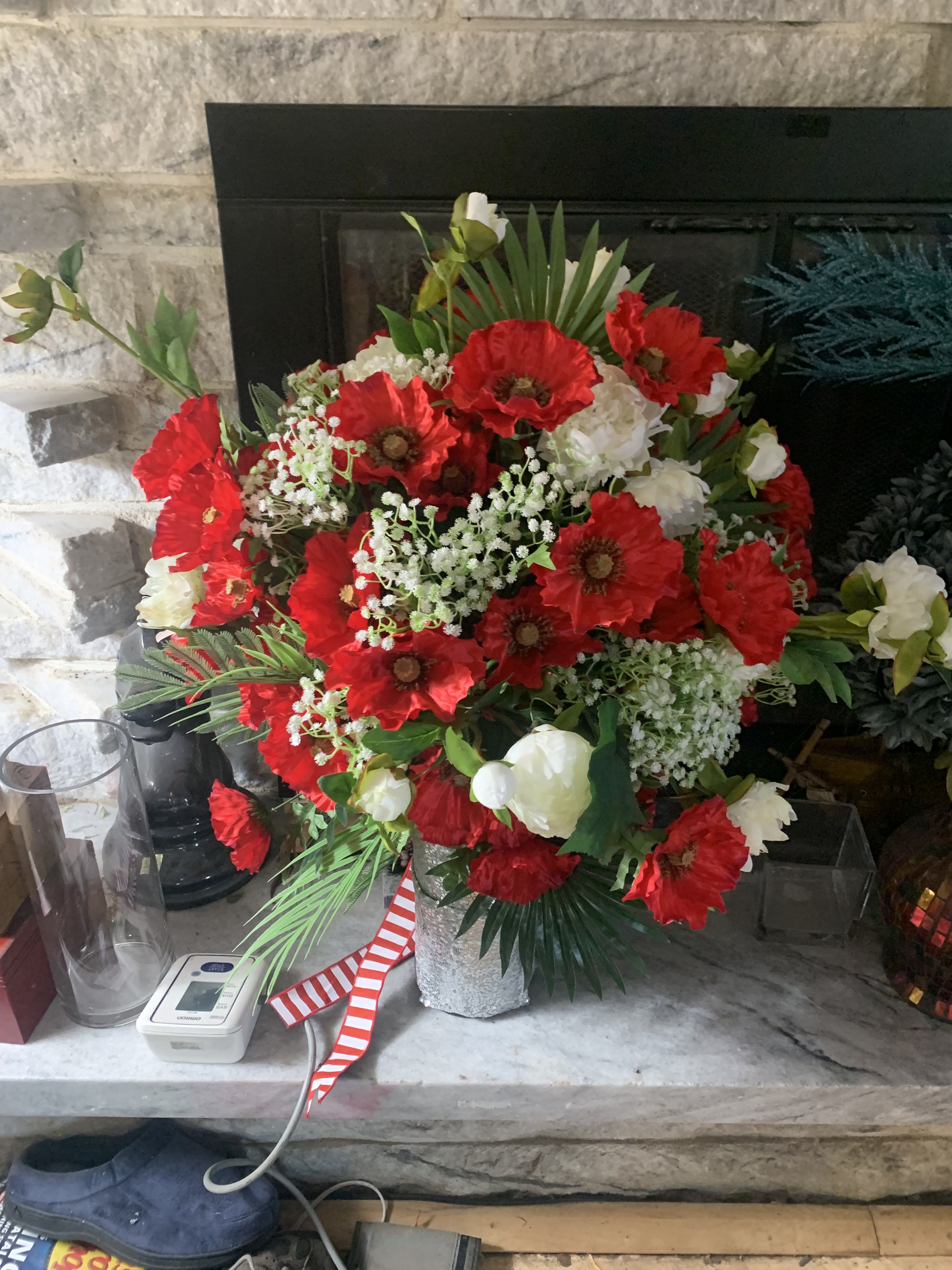 4th of July Fireworks - Bright, bold clusters of red poppy-like blooms explode against crisp white roses and carnations in this 4th of July Fireworks flower arrangement - a festive centerpiece for Independence Day, summer celebrations, or a patriotic birthday bouquet. The red-and-white color story reads lively and confident; the person you send this to will feel celebrated and noticed the moment it arrives.  This full, rounded arrangement pairs vivid scarlet blooms with airy white filler and rich greenery, including palm fronds that give height and a slightly tropical edge. It's presented in a textured silver vase and tied with a red-and-white striped ribbon for a classic, decorative finish. Ideal for birthdays, thank-you gestures, congratulations, or any summer gathering, it's designed to stand out on a mantle, table, or gift table with immediate visual impact and easy care.