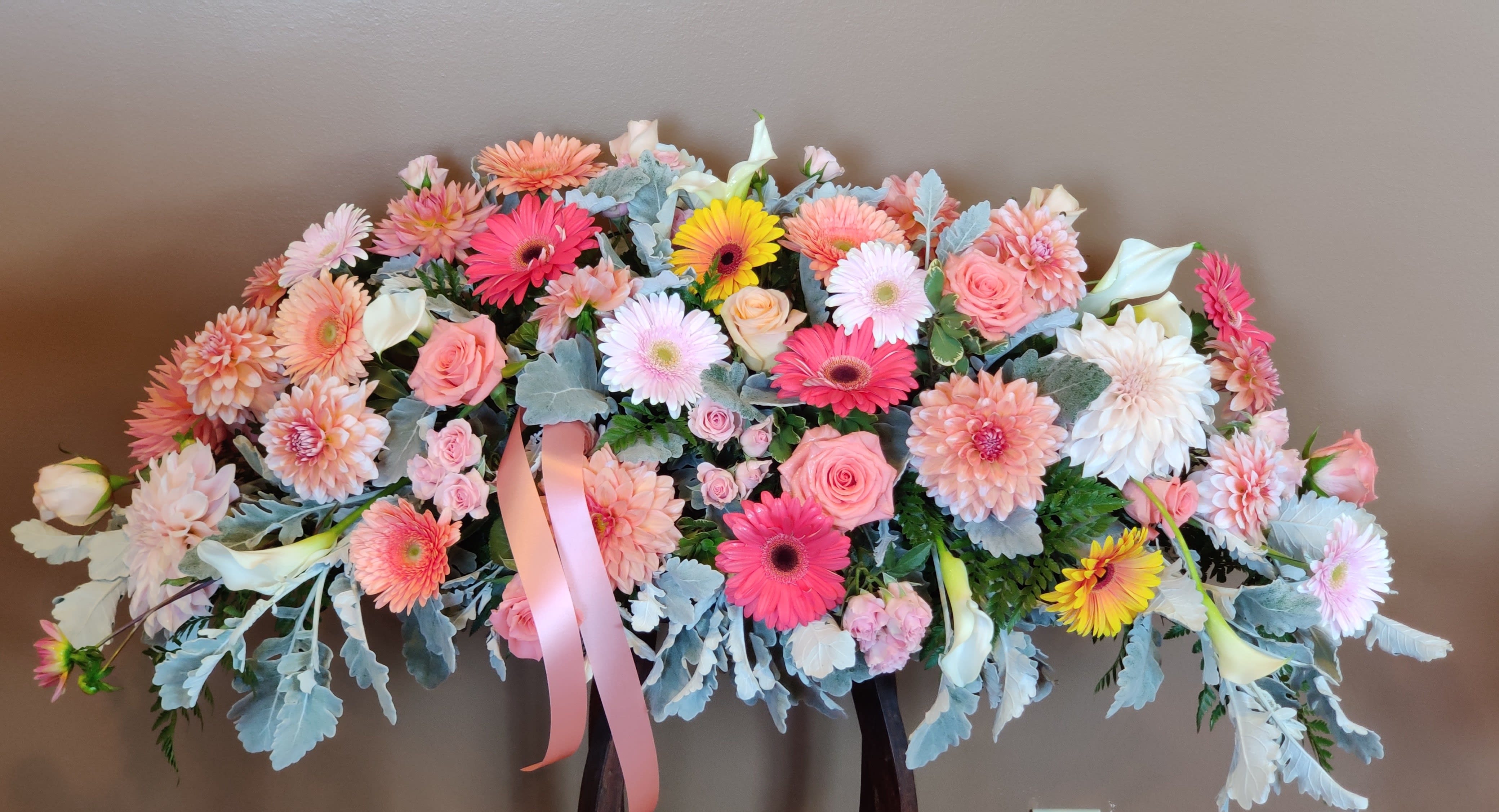 Large pastel floral arrangement with pink and white blooms and ribbon
