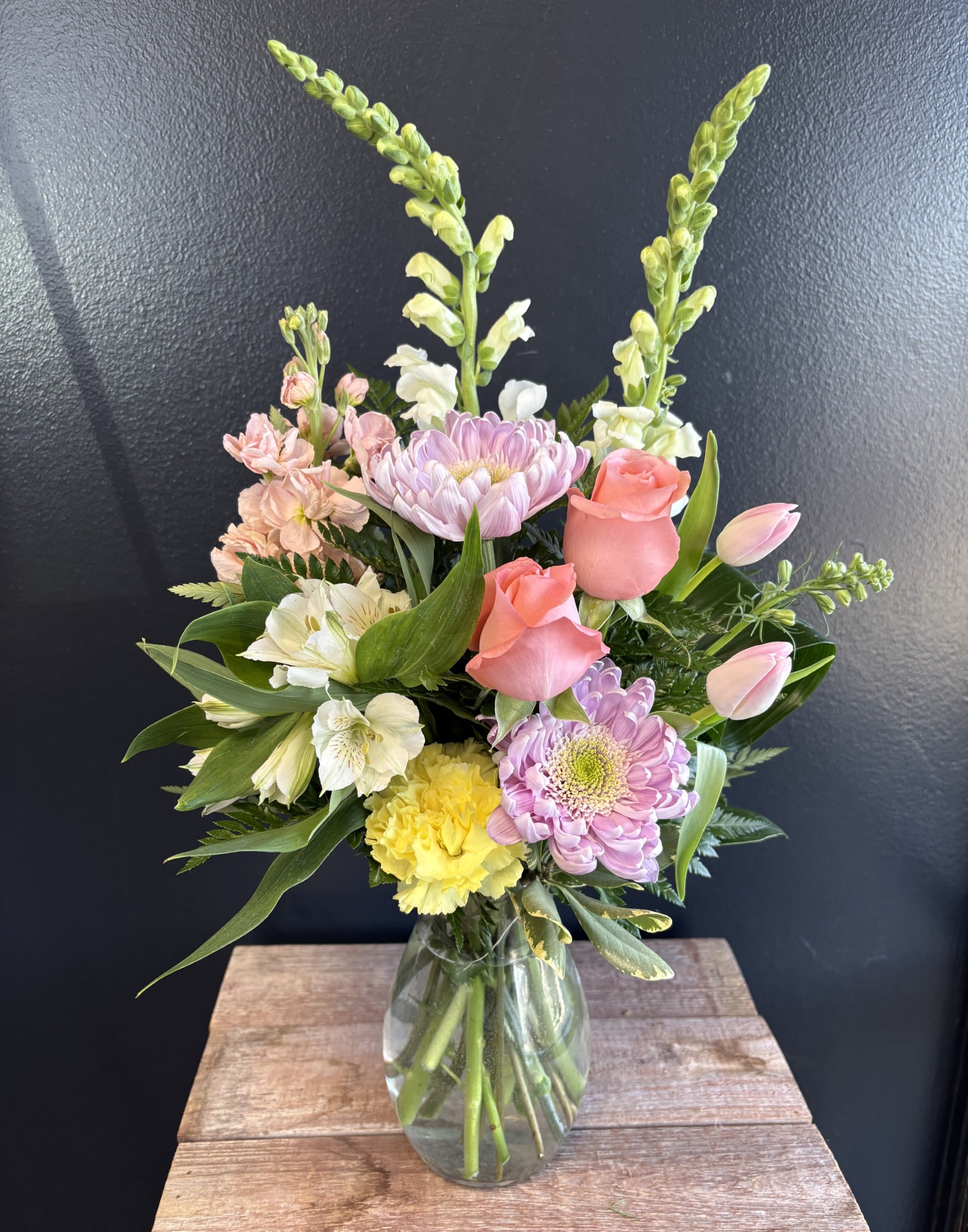 Mixed bouquet in a glass vase with pink roses, lilies, and pastel blooms