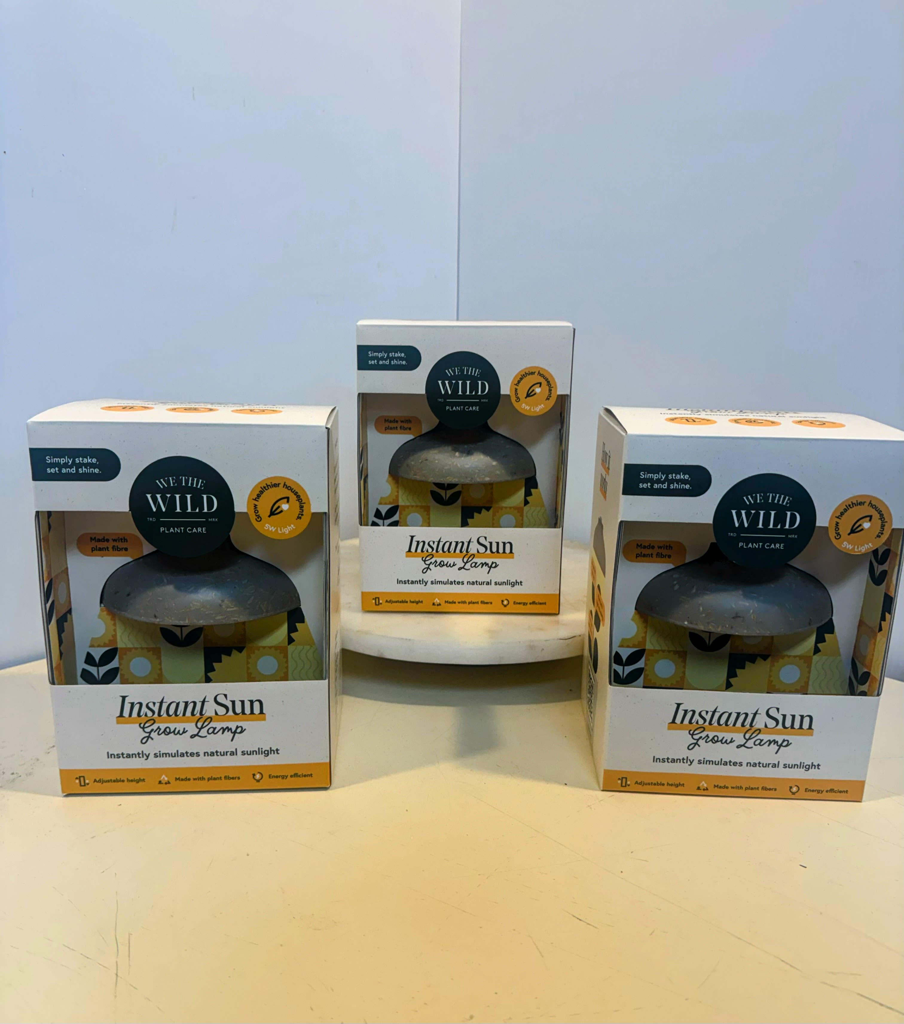 Three boxed grow lamps on a table.