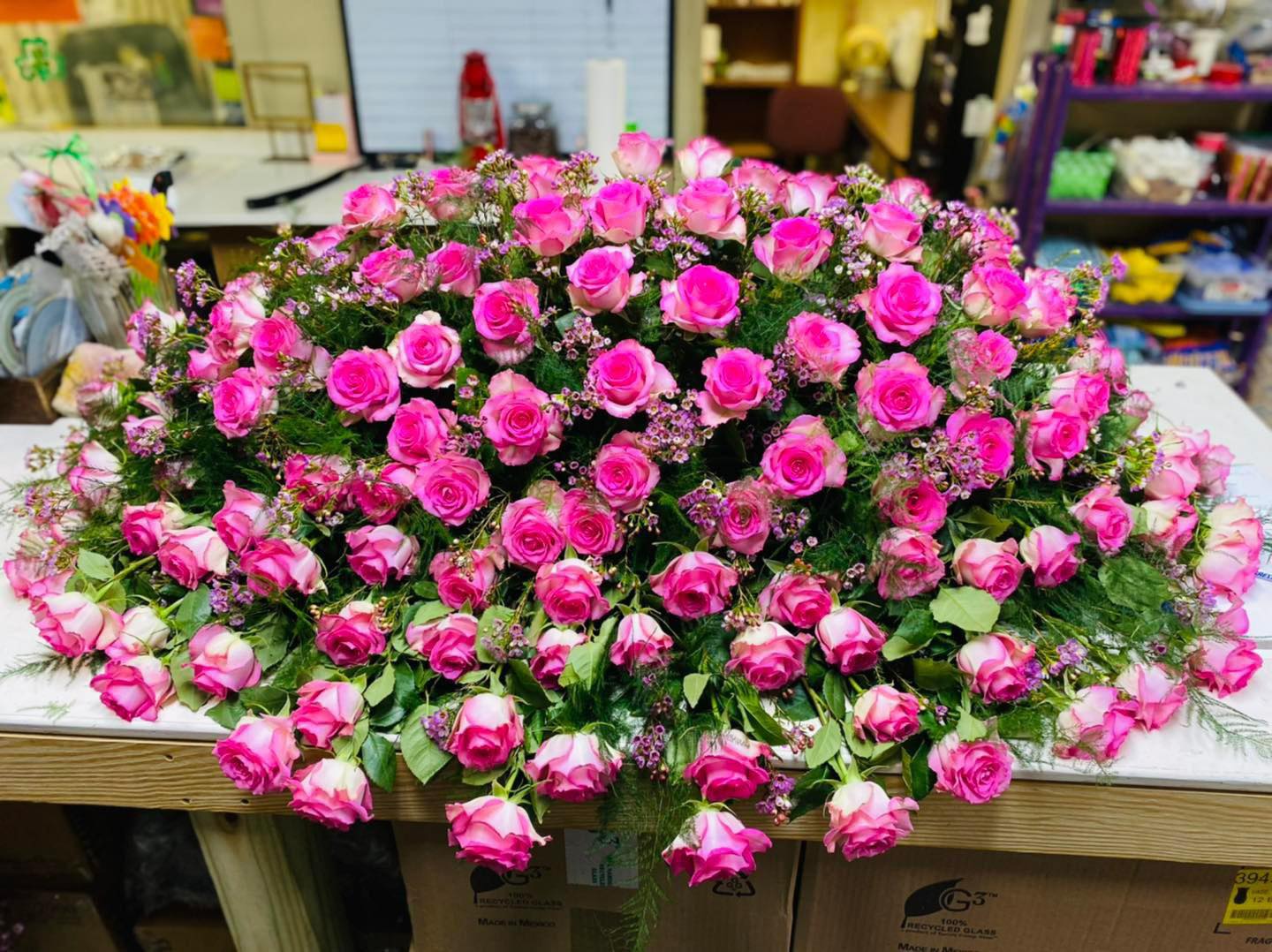 Large mound of pink roses with small filler flowers on a table