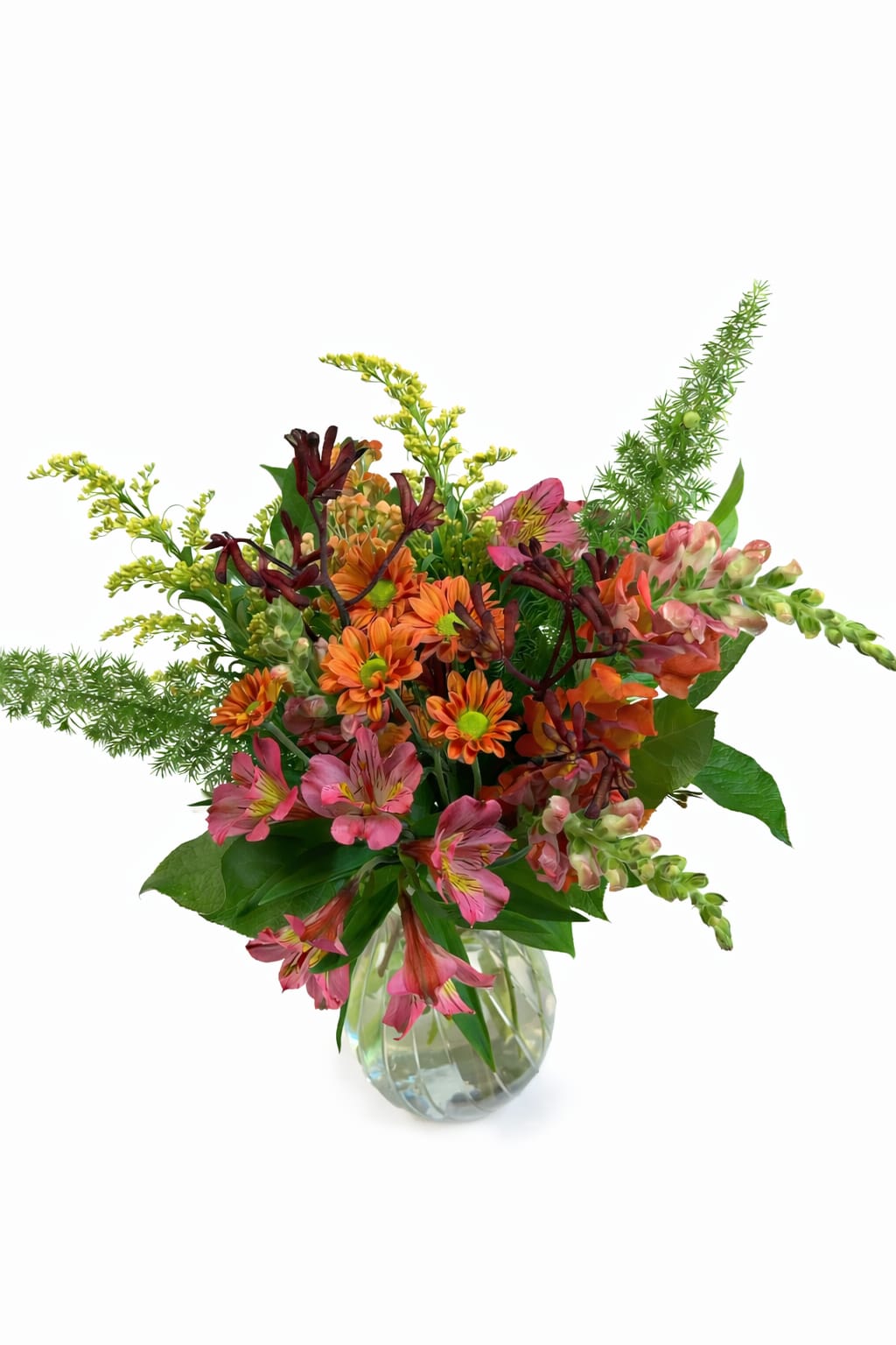 Mixed pink, orange, and burgundy flowers in a clear glass vase