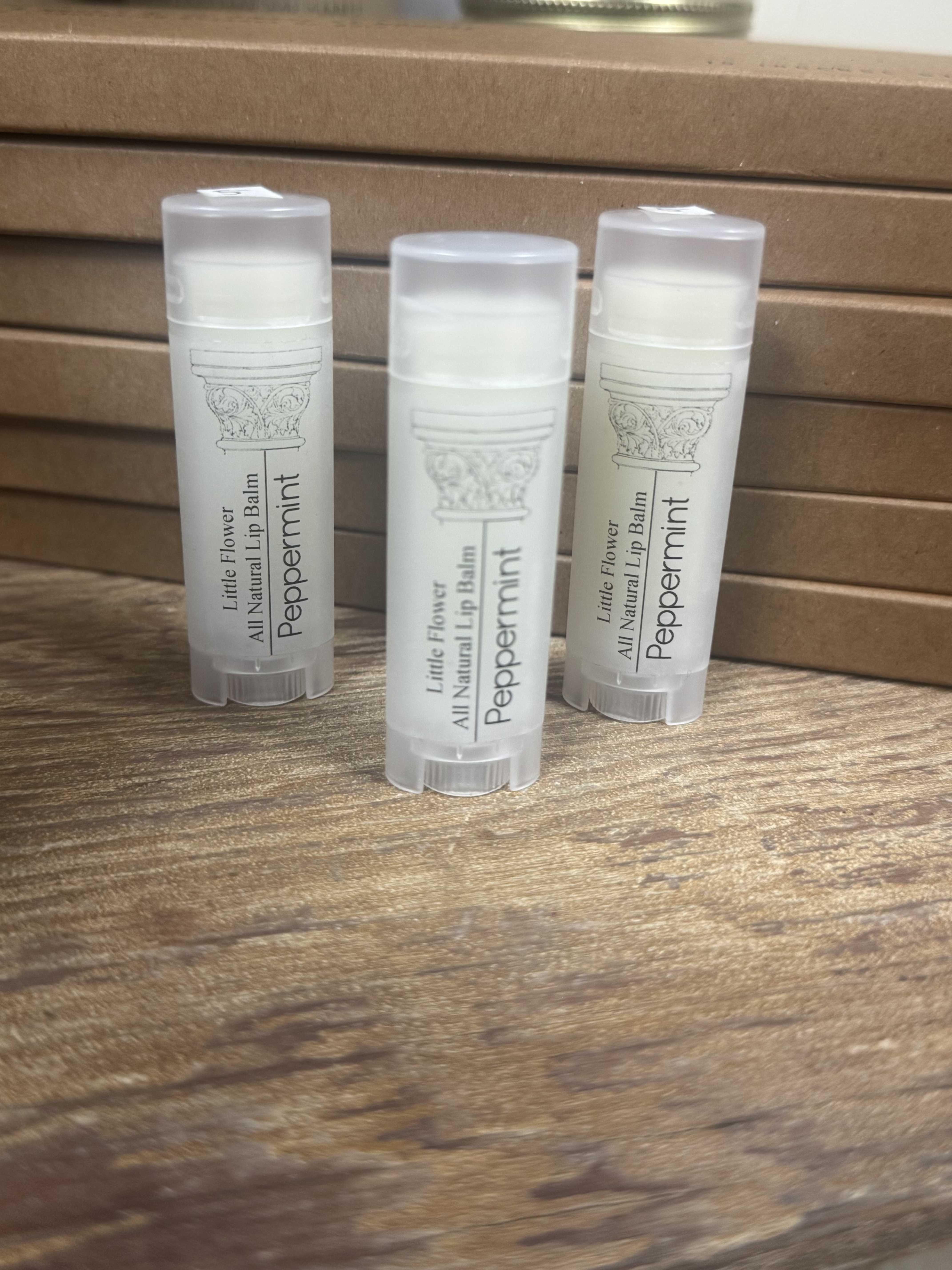 Three peppermint lip balm tubes on a wooden surface