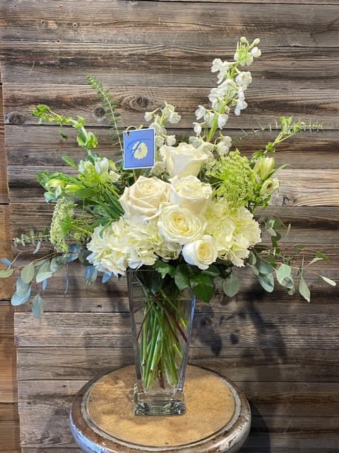 White roses and pale blooms arranged in a clear glass vase