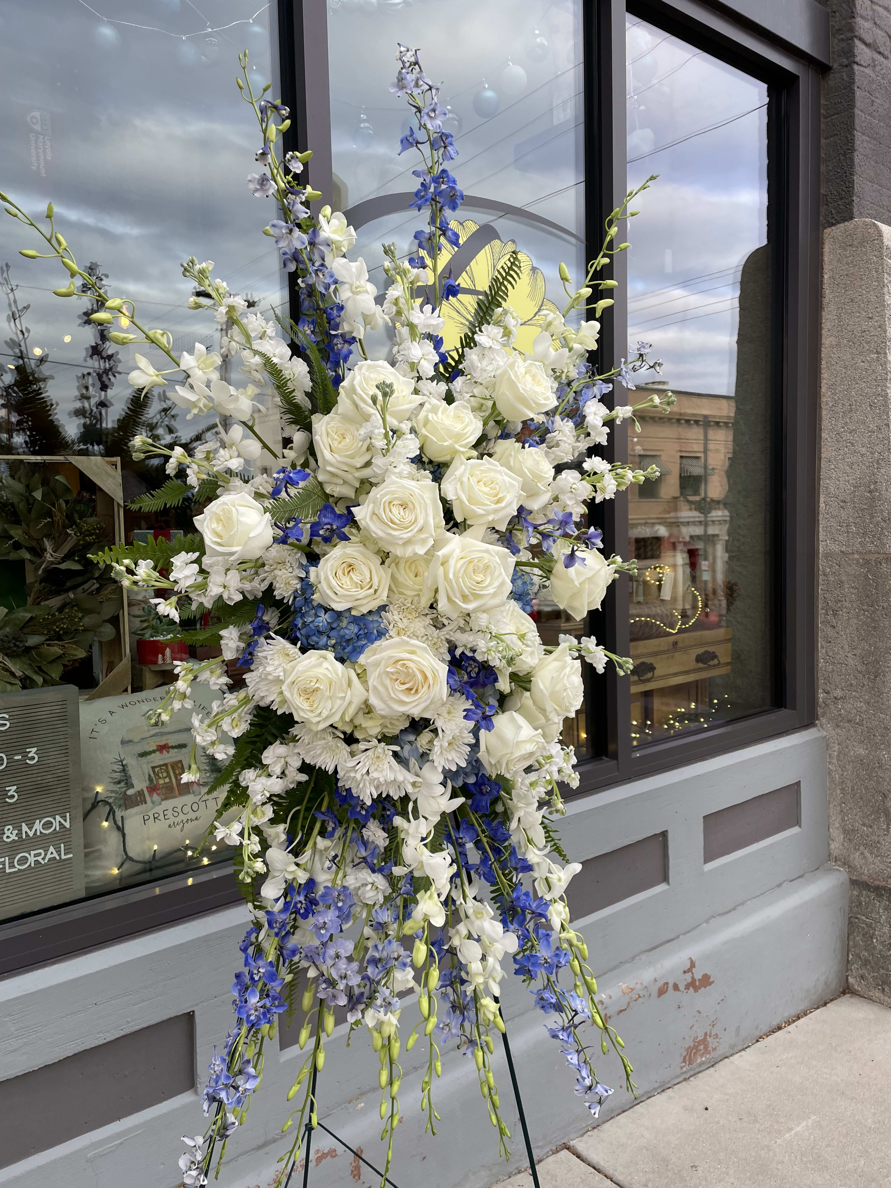 Tall floral spray with white roses and blue flowers on a stand