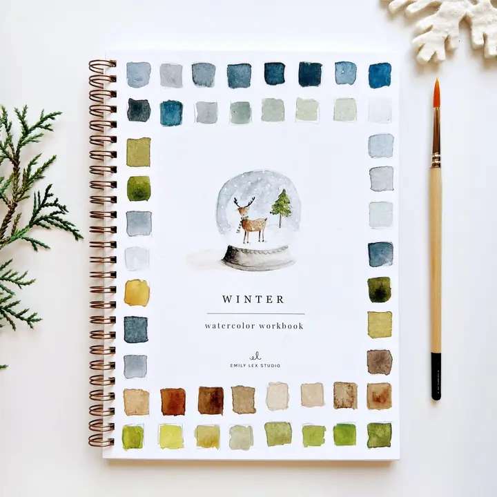 Winter watercolor workbook with a deer illustration, paintbrush, and color swatches