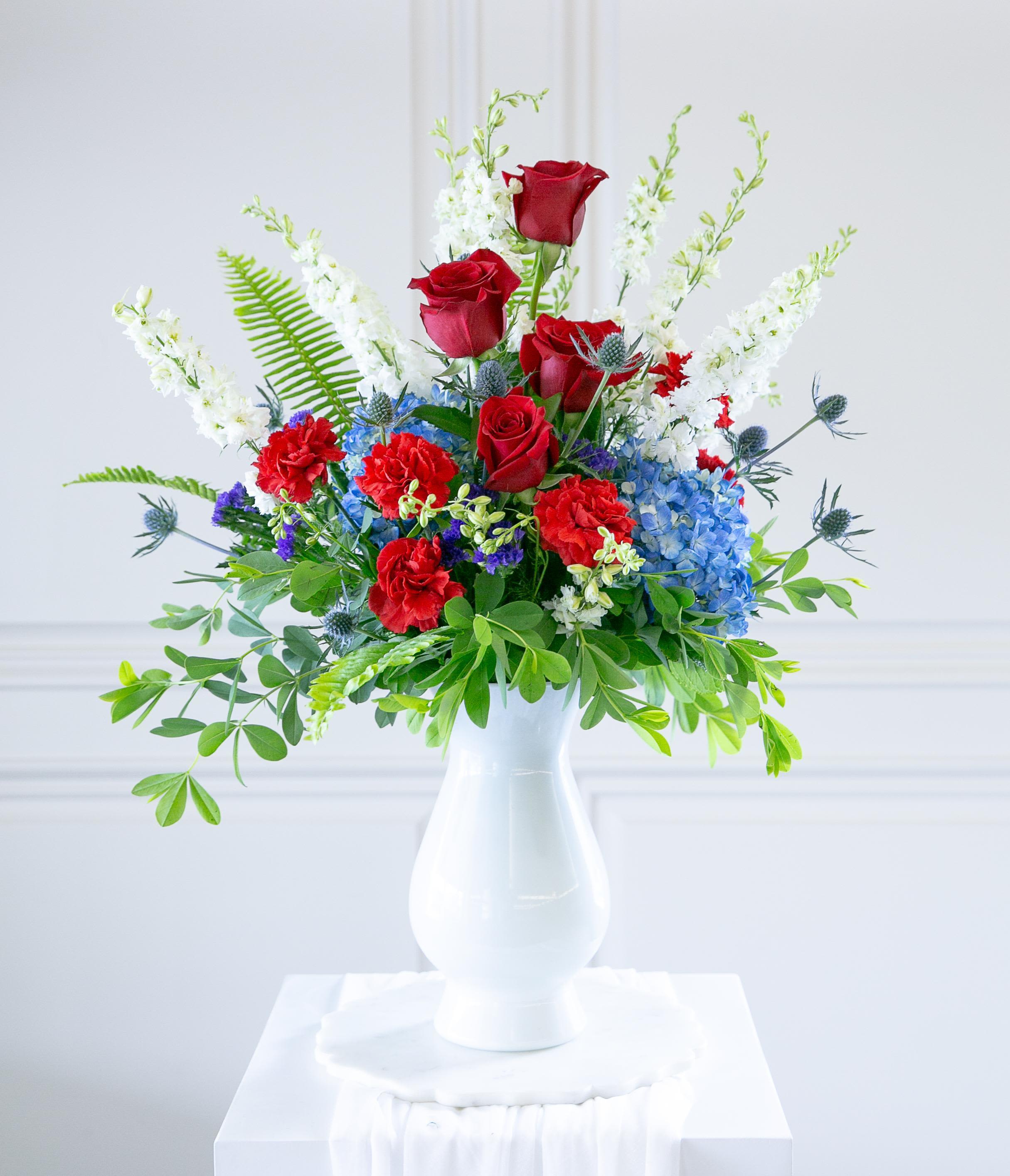 Red roses and blue hydrangeas in a white vase