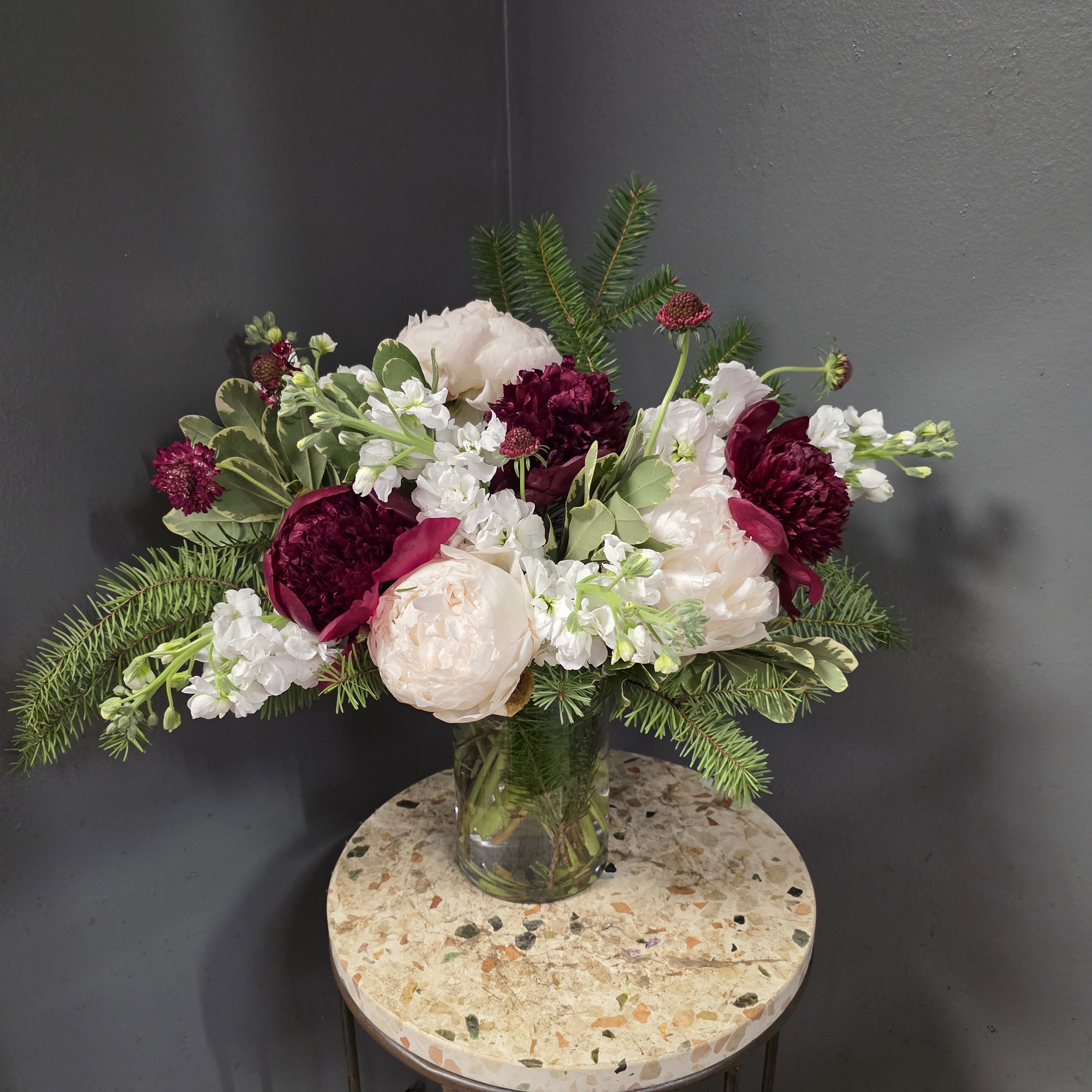 Bouquet of blush and burgundy flowers in a clear glass vase