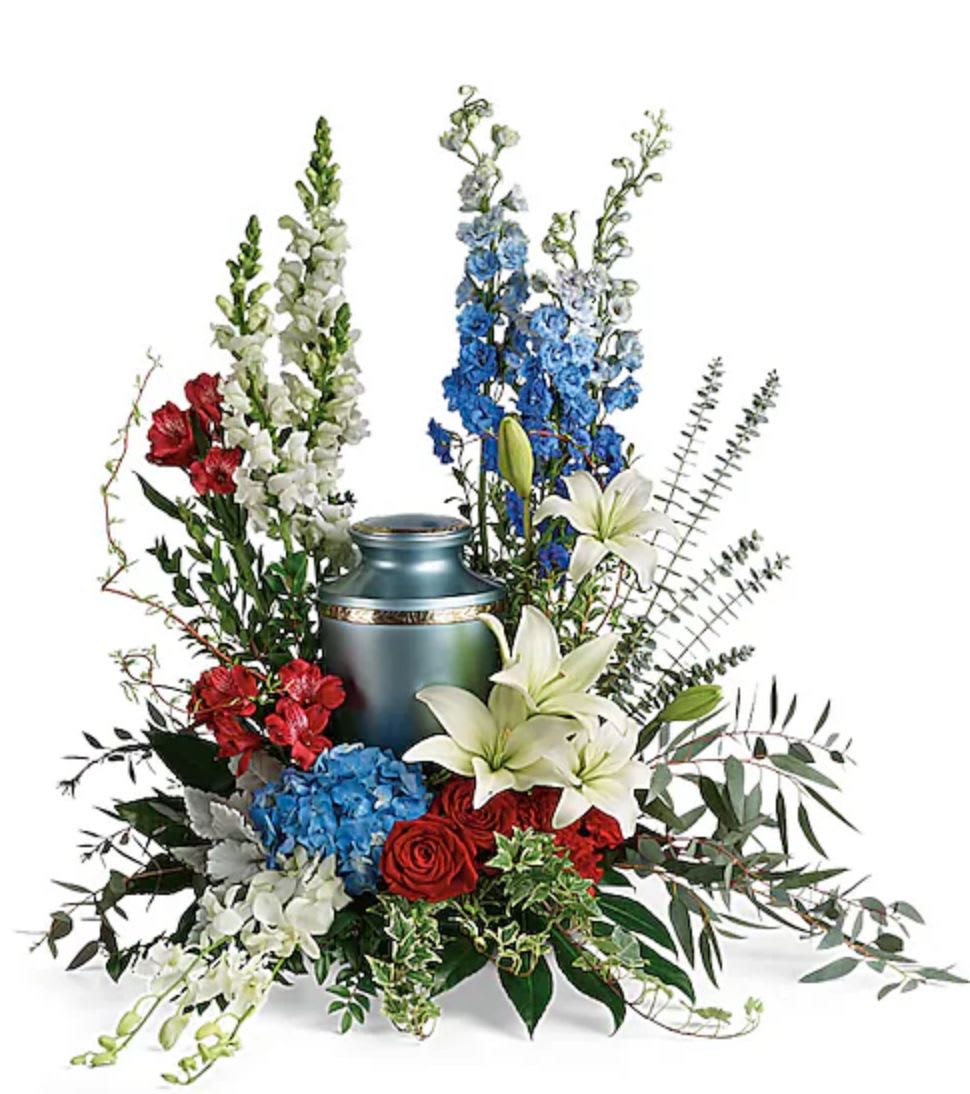 Floral arrangement around a blue urn with red, white, and blue flowers