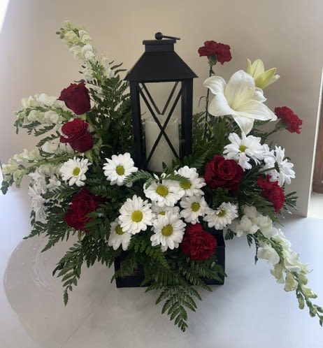 Everlasting Light of Love - Everlasting Light of Love is a heartfelt tribute that offers comfort, remembrance, and hope. Centered around a beautiful LED candle lantern with an included remote for convenient operation, this meaningful arrangement features rich red roses and red carnations accented with elegant white lilies, white snapdragons, and white daisies. Together, these blooms symbolize enduring love, peace, and cherished memories.  Thoughtfully designed as a lasting expression of sympathy, Everlasting Light of Love provides a beautiful way to honor a loved one's memory. Long after the fresh flowers have been enjoyed, the keepsake lantern serves as a gentle reminder that the light of love continues to shine.