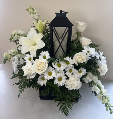 Eternal Light of Hope - Eternal Light of Hope is a graceful tribute that offers comfort, peace, and lasting remembrance. Centered around a beautiful LED candle lantern with an included remote for convenient operation, this elegant arrangement features pristine white roses, white carnations, white lilies, white snapdragons, and white daisies. Together, these timeless blooms symbolize hope, peace, purity, and the enduring memory of a cherished loved one.  Thoughtfully designed as a meaningful expression of sympathy, Eternal Light of Hope provides a beautiful way to honor a life well lived. Long after the fresh flowers have been enjoyed, the keepsake lantern serves as a gentle reminder that hope and treasured memories continue to shine.
