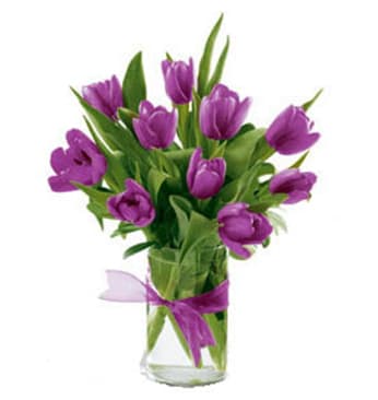 Purple tulips in a clear glass vase with a purple ribbon bow