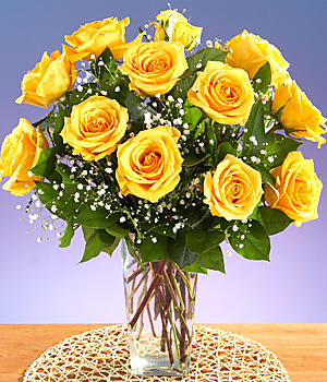 Arrangement of yellow roses with white filler flowers in a clear glass vase