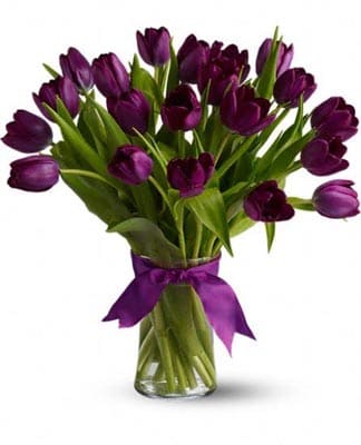Arrangement of dark purple tulips in a clear glass vase tied with a purple ribbon