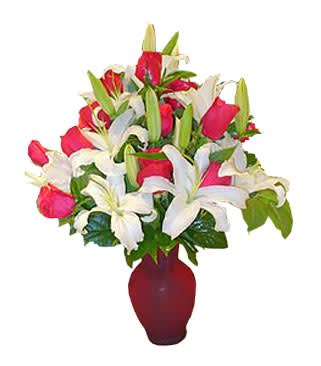 Arrangement of red roses and white lilies in a red glass vase