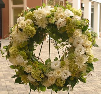 Large wreath of white and green flowers displayed on a metal easel stand